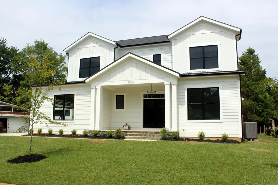 White board-and-batten exterior with black Andersen windows on the Modern Farm House by Trophy Custom Homes