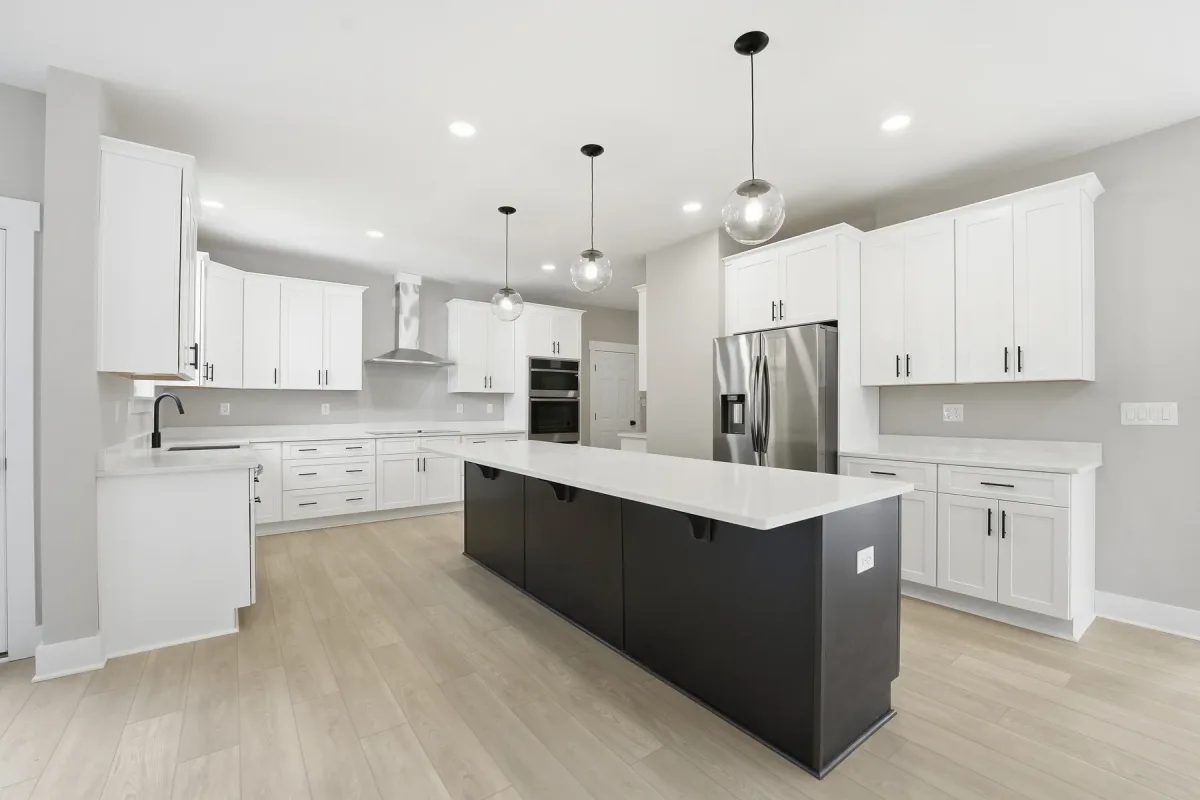 Kitchen with a dark island, white cabinetry and pendant lights