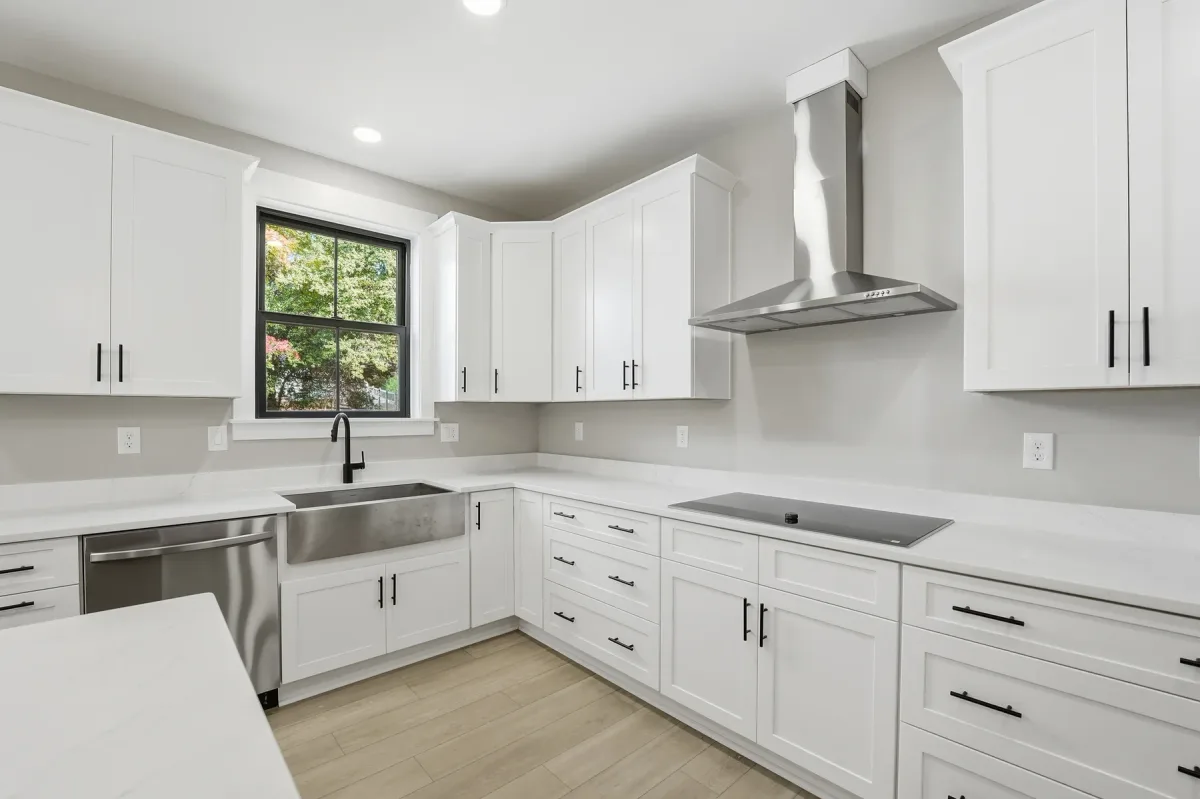 Kitchen cabinetry, range hood and window above the sink