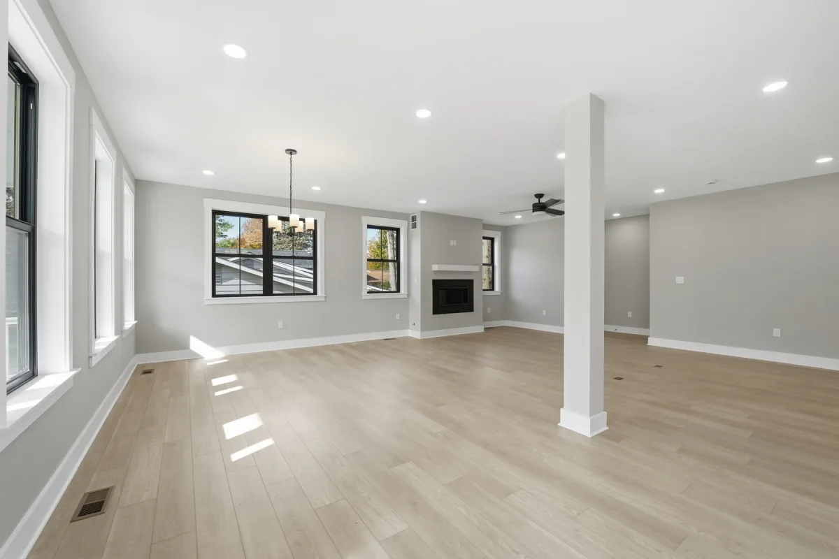 Open living area with pale floors and black-framed windows